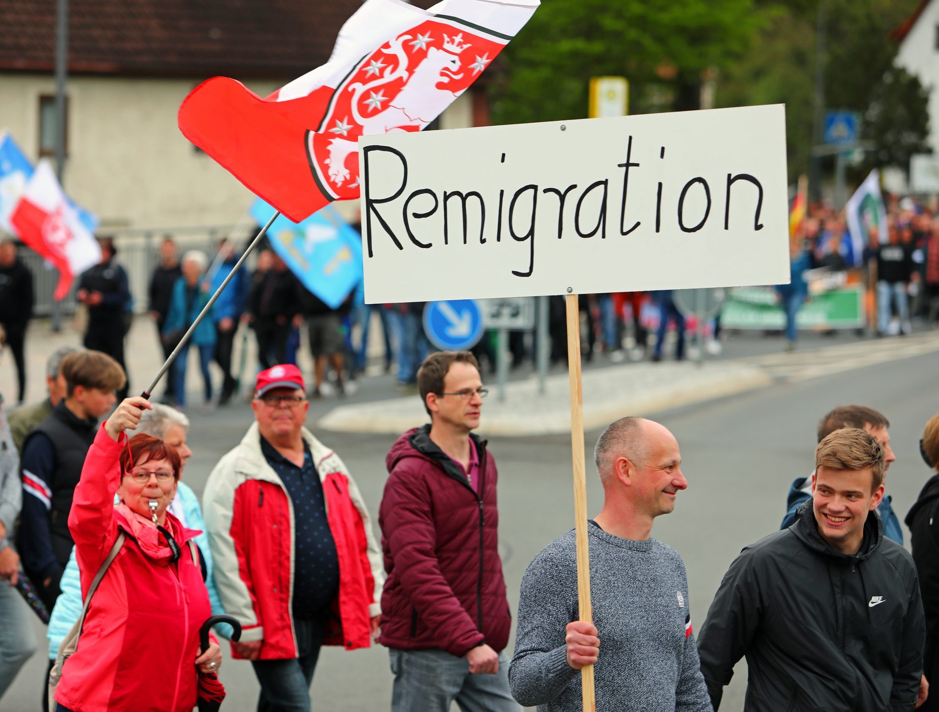 Bilder einer Demonstration. Auf einem hochgehaltenen Schild steht "Remigration"