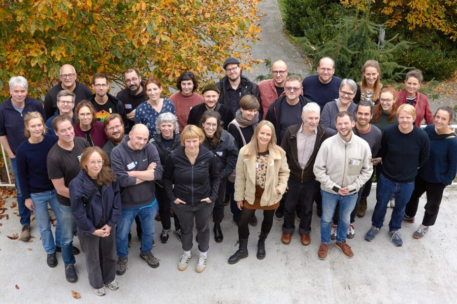Ein Foto von der Vollversammlung des Bundesverbands Mobile Beratung im Oktober 2025: Mehrere Menschen stehen vor Bäumen.